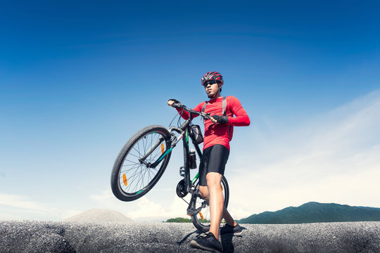Young man riding mountain bike on the background of mountains at blue sky © Aunging