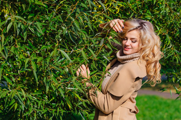 Beautiful elegant woman standing under the tree in autumn park