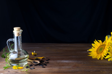 Sunflower seeds in a wooden spoon and sunflower oil and beautiful yellow sunflowers on a wooden...
