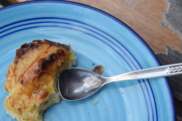 Blauer Teller mit Silberlöffel und einem Stück Kuchen auf einem Gartentisch