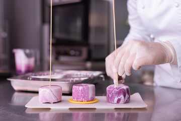 Three cakes. Master of confectionary feeling satisfied while placing three blueberry cakes on plate