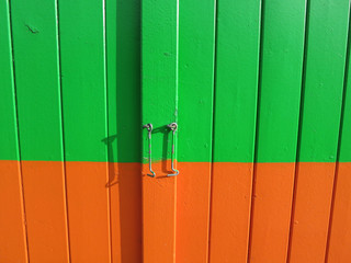 green and orange painted wooden door with a little hook