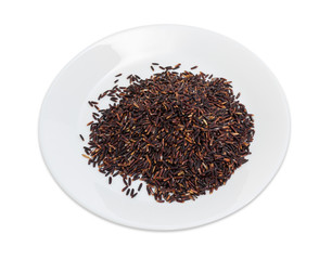 Uncooked black rice on the white dish on white background