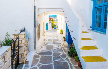 Colorful stairs in narrow street with white houses and blue colored windows. Old rustic Greek house exterior, Lefkes, Paros Island