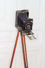 Old large format photographic camera with bellows on wooden tripod