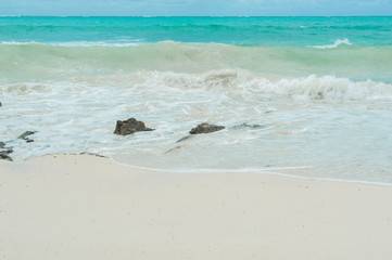 Turquoise waves of the Indian ocean run on the white beach of the island of Zanzibar