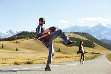 Happy young couple having fun with longboard on the road. Young man and woman skating together on a sunny day. © Kirill