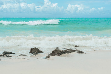 Turquoise waves of the Indian ocean run on the white beach of the island of Zanzibar
