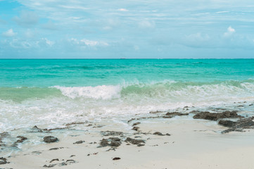 Fototapeta na wymiar Turquoise waves of the Indian ocean run on the white beach of the island of Zanzibar