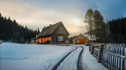 Wooden hut in winter forest at dusk. Rustic house for tourists in mountains in the night
