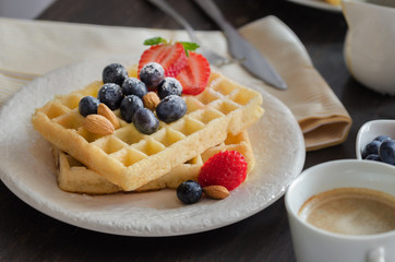 Close up of Belgian waffles  decorated wirh strawberries, blueberries ,almond and icing sugar.  . Delicious homemade dessert  for breakfast.