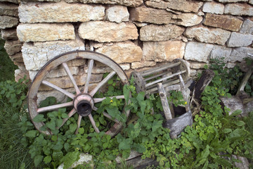 Fototapeta na wymiar Open air museum of antique peasant things, old wheel near the brick wall