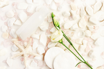 
Light delicate Spa background with white stones, bottle of skincare product, cleansing cotton pads and fresh flower.