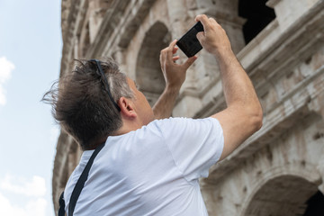 Male tourist taking a photo of the famous Roman monument the Colosseum or Flavian Amphitheatre