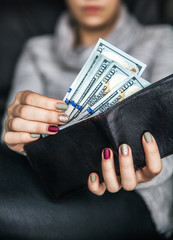 In the women's hands is the leather wallet with a wad of hundred dollars. Business offer. Beautiful manicure