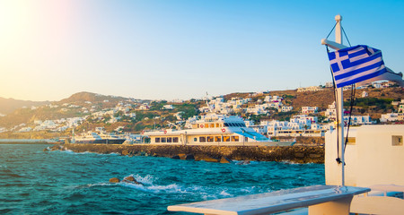 View of the harbour with greek flag at sunset at Mykonos island
