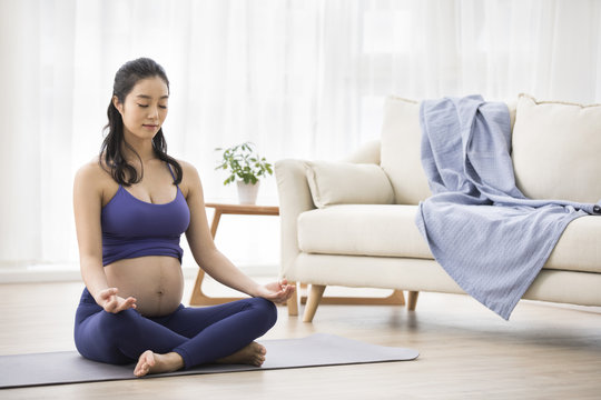 Cheerful pregnant woman practicing yoga at home