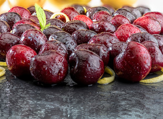 Precious red and fresh cherry pints, fresh and raw on a textured and veined black background. With lemon yellow zest.