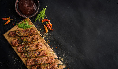 Grilled kebab with spices and sauce on a dark background