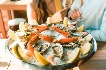 Close-up of fresh oysters and crabs served on ice with slices of lemon at the table of a romantic...