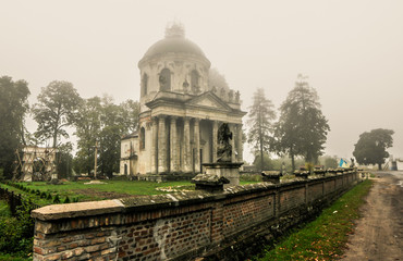 Misty view of Roman Catholic church Exaltation of the Holy and St. Joseph near Pidhirtsi village, Lviv, Ukraine. Old church in couryside at dawn