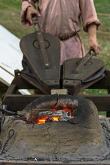 Blacksmithing, a red-hot piece of iron in a forge furnace, blacksmith with bellows