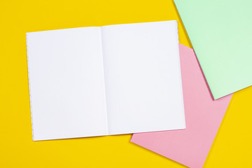 Open notebook and colorful notebooks on yellow background