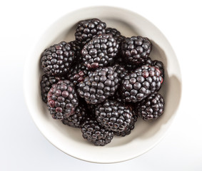 Delicious fresh blackberries and ripe black and reddish garnet. In white bowl and isolated background.