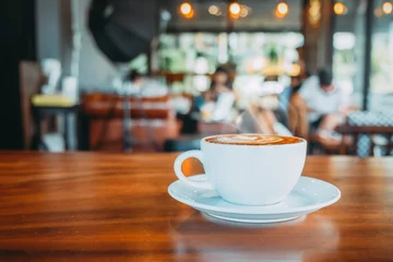 Fototapeten Weiße Tasse heißen Kaffee auf dem Tisch im Café mit Menschen. Vintage- und Retro-Farbeffekt - geringe Schärfentiefe © jakkapan