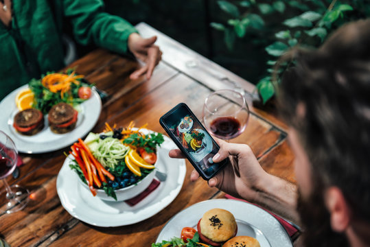Man Photographing Food In A Restaurant