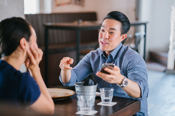 A portrait of a young and lovely Asian Chinese couple on a date. Both are having a good time talking to one each other.
