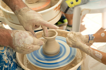 The potter's hands make a ceramic vase on a potter's wheel