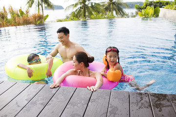Happy young family having fun in swimming pool
