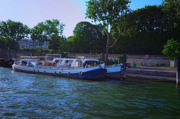 Fototapeta na wymiar The picturesque embankment of the Seine River with residential barges during sunset. View from tourist boat. Paris, France