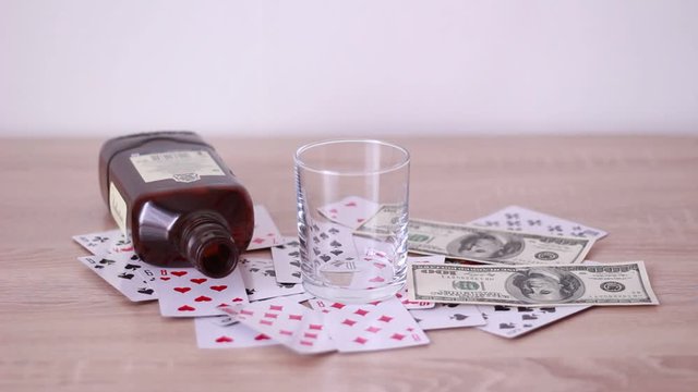 Dollar banknotes, playing cards, glass and empty bottle