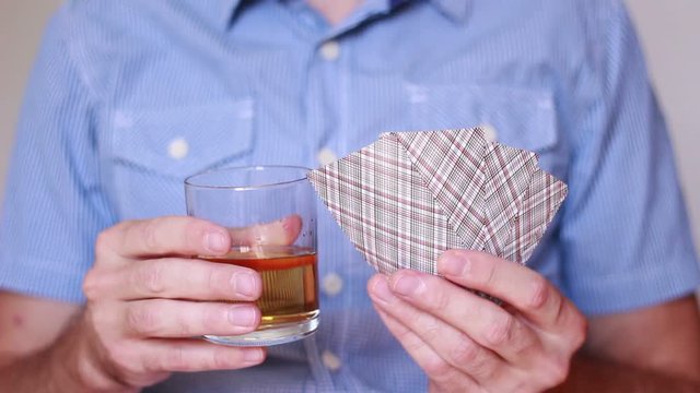 Holding whisky and playing cards in hands