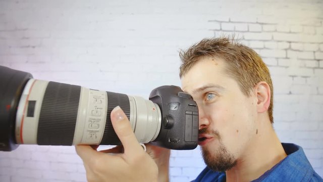 Douchebag photographer making fun in slow motion 4K. Portrait of man in focus with funny face expression holding the photo camera next to it making fun with it.