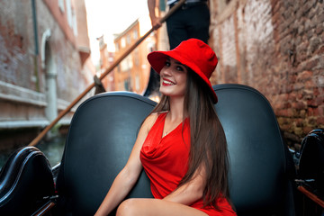 Beutiful woman in red wear riding gondola in Venice