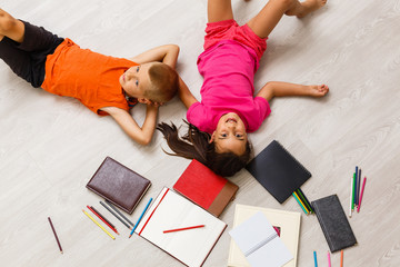 Kids reading for school lying on floor at home