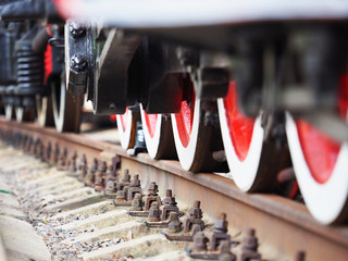 Old steam train wheels approaching, close-up, view from a railway. Black and red. Rails and sleepers
