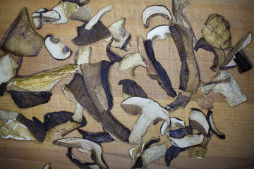 Dried domestic mushrooms collected in the forest. Dried mushrooms prepared for cooking or for seasoning food. Mushrooms cut into slices lying on a wooden plank.
