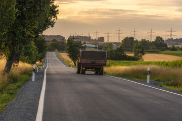 Country road and a truck with grains at sunset