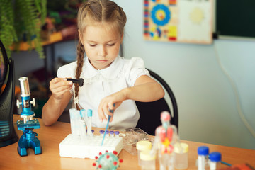 Little girl study with microscope doing chemical experiments in classroom