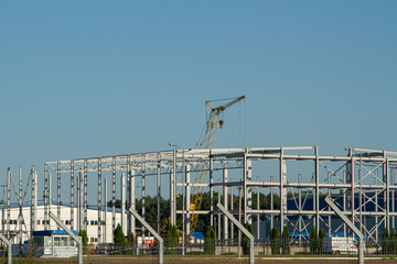 Construction of a logistics center of steel beams. Construction of metal structures. Construction of warehouses from a metal profile. Use of a tower crane when installing the frame of a building.