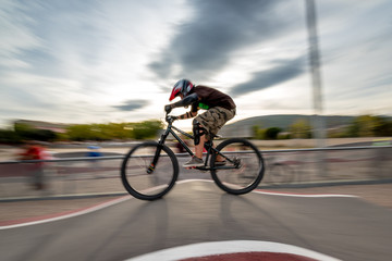 A biker rides at a pumptrack during sunset. Motion enhanced with a swipe technique.