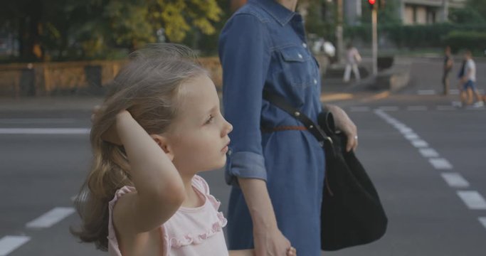 Young mother and her little preteen daughter waiting at the pedestrian crossing light