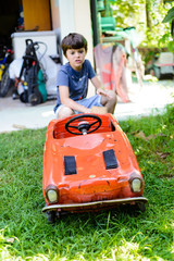 child cleans red tin toy car in the garden