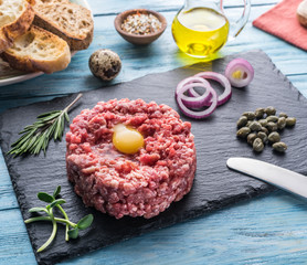 Steak tartare served with raw quail egg yolk, capers and bread. Meat dish.