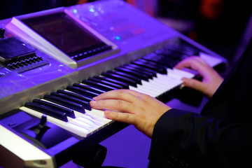 The electronic keyboard musical instrument, the synthesizer and the hands playing it.
