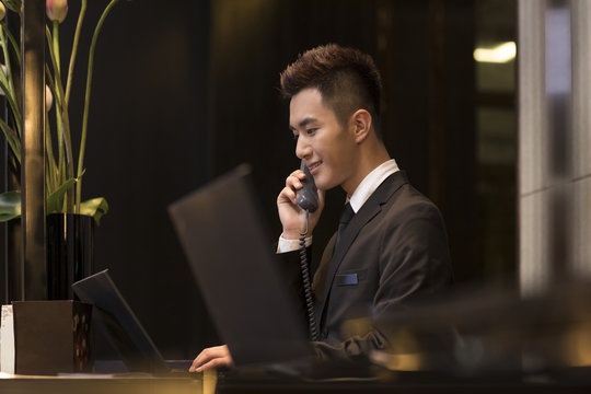 Cheerful hotel receptionist talking on the phone - Powered by Adobe
